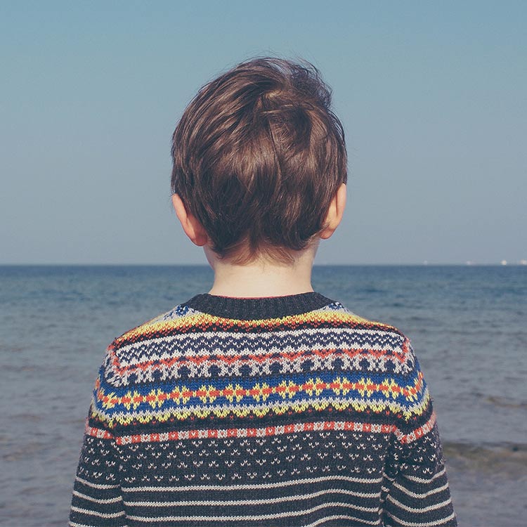 Boy_wearing_jumper_looking_out_to_sea